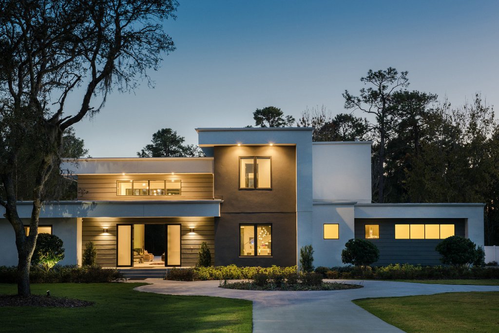 Modern home at dusk with warm exterior and interior lighting