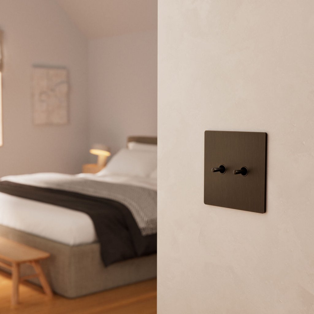 Bronze toggle light switch beside a calm bedroom